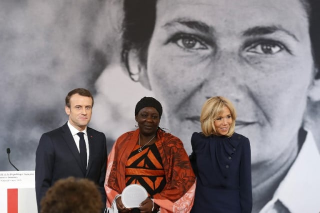 Cameroonian activist Aissa Doumara Ngatansou (C) poses for a photo with French President Emmanuel Macron (L) and his wife Brigitte Macron (R) after she received the Simone Veil prize, at the Elysee Palace, in Paris, on March 8, 2019 during International Women's Day. Aissa Doumara Ngatansou has worked against forced marriages and other violence against girls and women. Thibault Camus / POOL / AFP