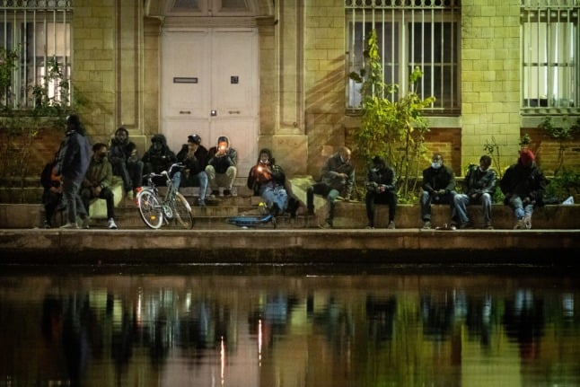 Crack smokers light their crack pipes on the docks at Stalingrad Square in Paris.