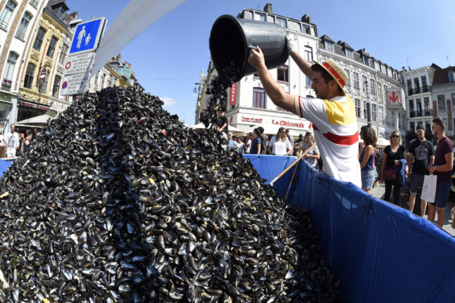 An employee of "La Chicoree" restaurant empties a bucket of empty mussel shells onto a pile during the annual Braderie de Lille in 2018.