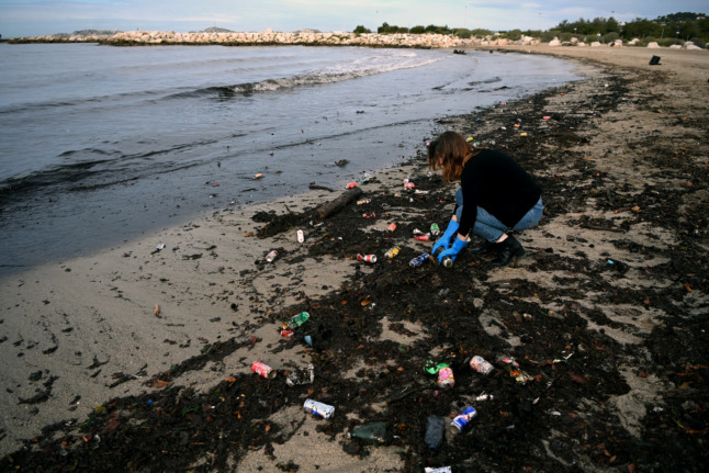 A woman collects waste on a beach after heavy rains and following a strike of waste collectors in Marseille.