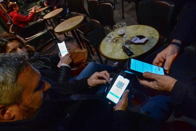 Customers at a bar in Saint-Malo, northwest France, have their digital health passes scanned by a police officer