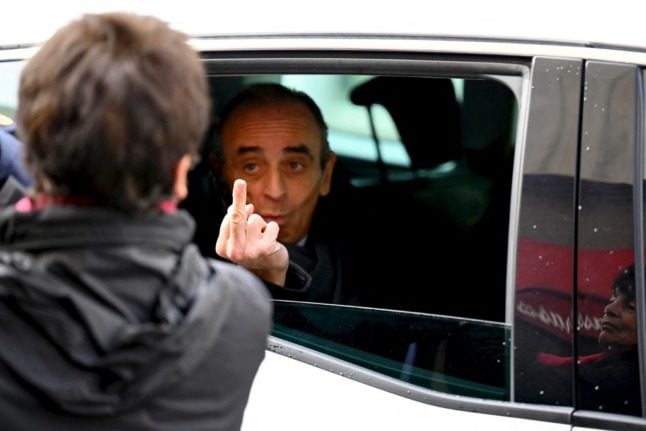 French far-right media pundit Eric Zemmour gives the finger as he leaves in his car.