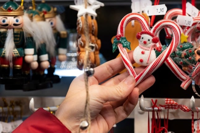 A woman holds up a decorations at a French Christmas market. 