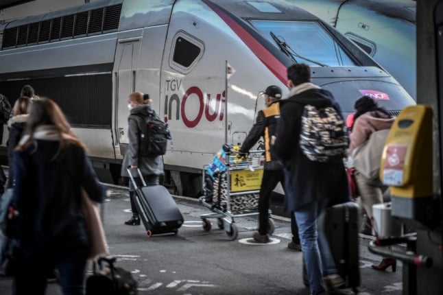 Travellers, in facemasks, head towards a train at Paris's Gare de Lyon