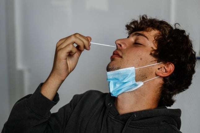 A man takes his own nasal swab sample.
