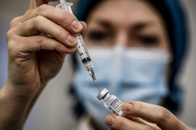 A medical professional prepares a syringe of Pfizer vaccine 