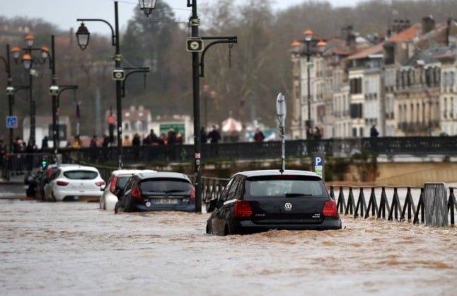 Partially submerged cars on a road running along the banks of the River Nive in Bayonne. 