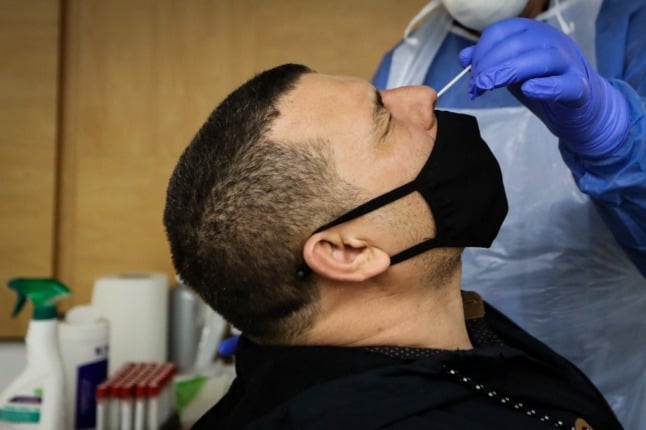 A medical professional performs a nasal swab on a patient