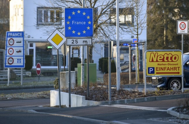 A blue sign with yellow stars indicating the French border with Germany