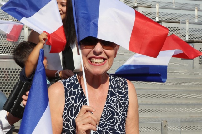 A lady waves a French flag during a political rally. 
