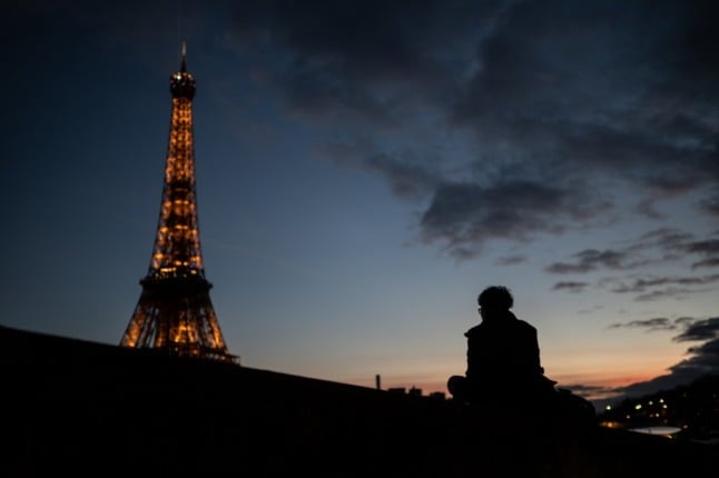 A man looks at the Eiffel Tower during sunset.