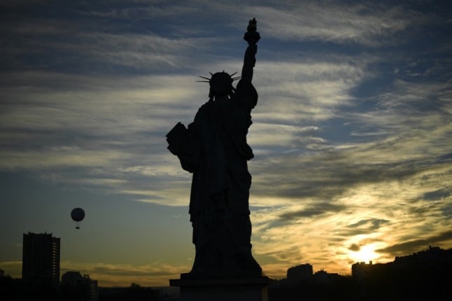 A replica of the Statue of Liberty stands on Paris' Ile de Cygnes during sunset 